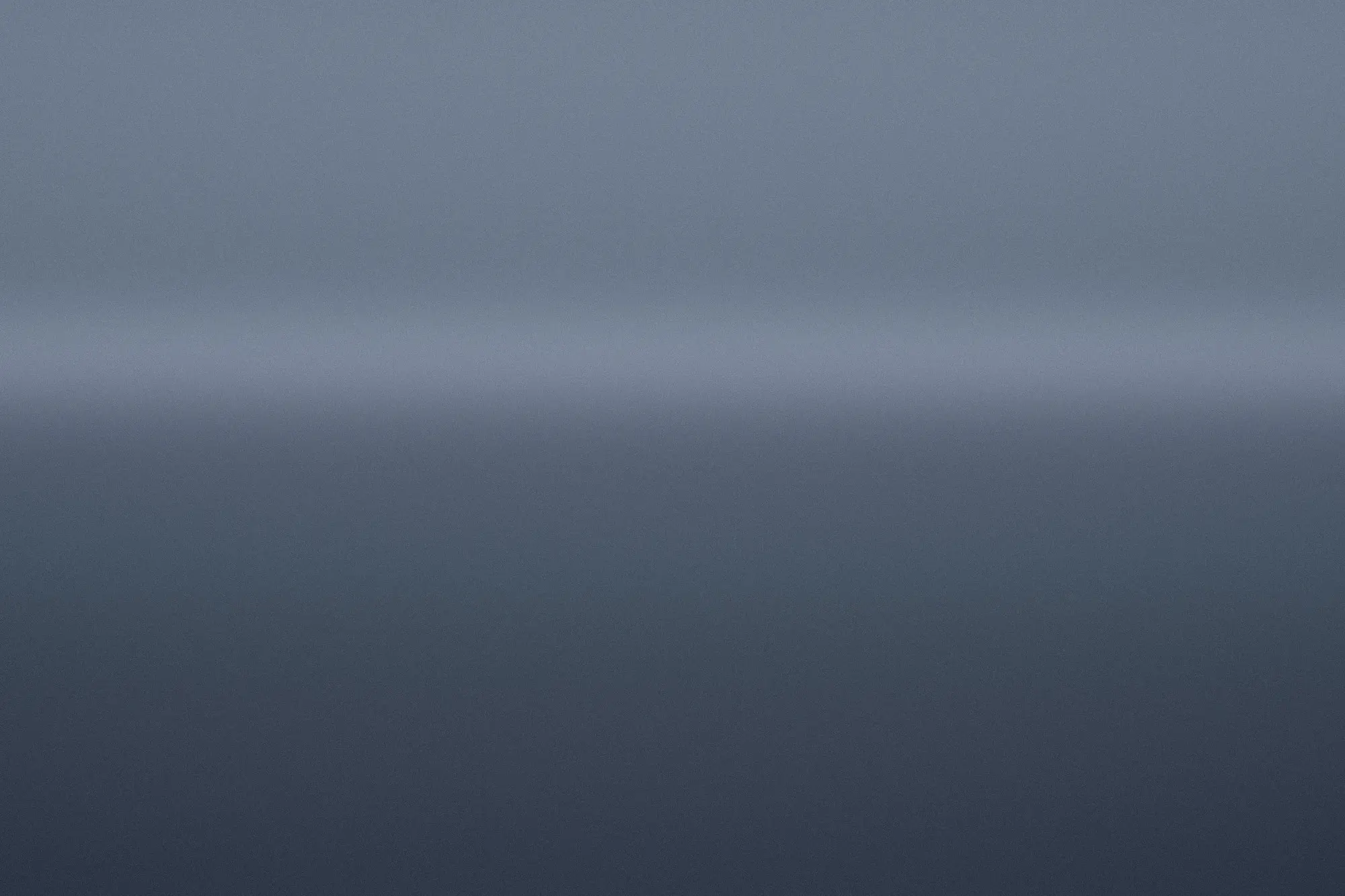 Blue-hour harbour water under a cool sky, a faint warmer band low on the horizon.