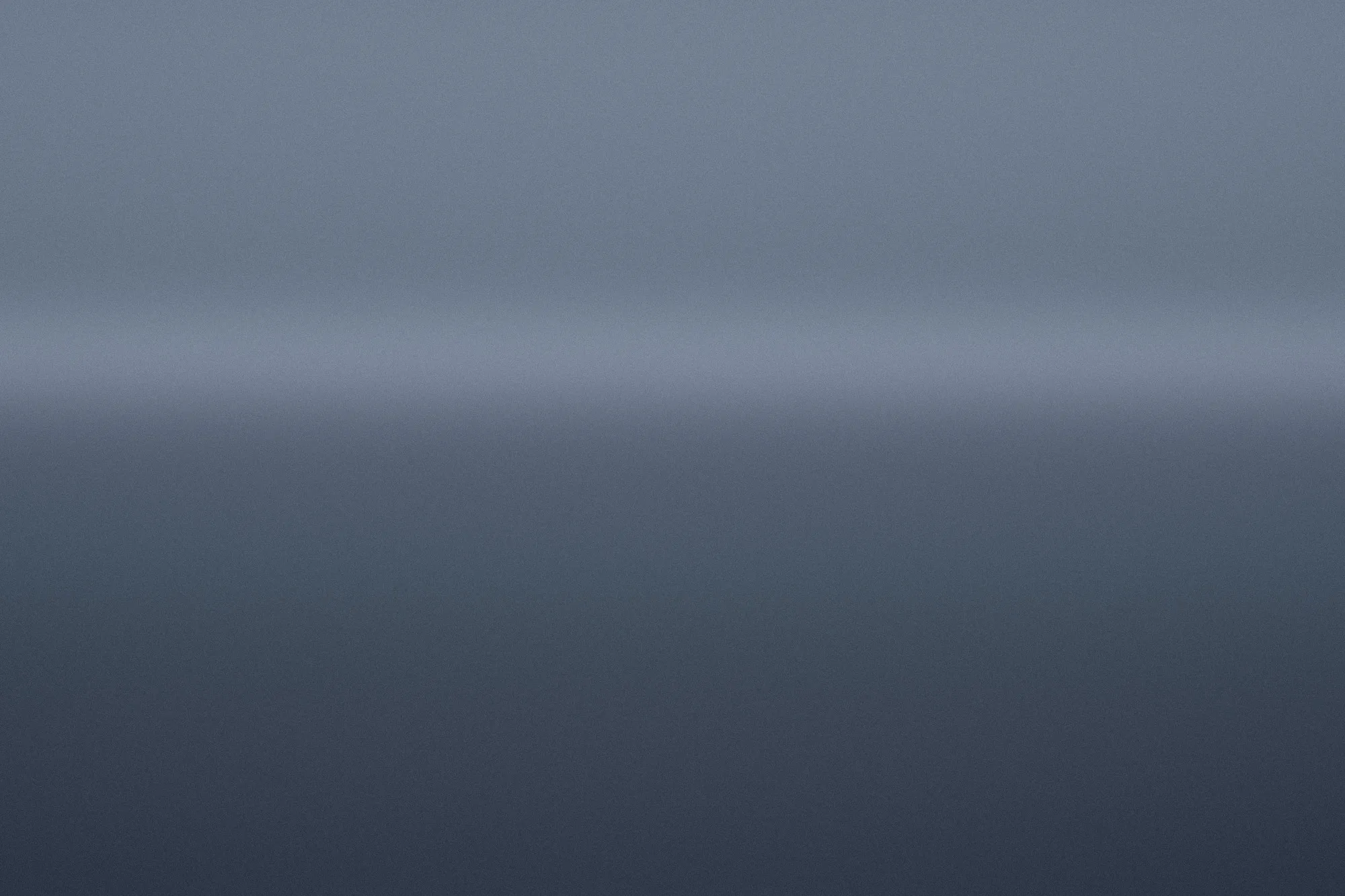 Blue-hour harbour water under a cool sky, a faint warmer band low on the horizon.